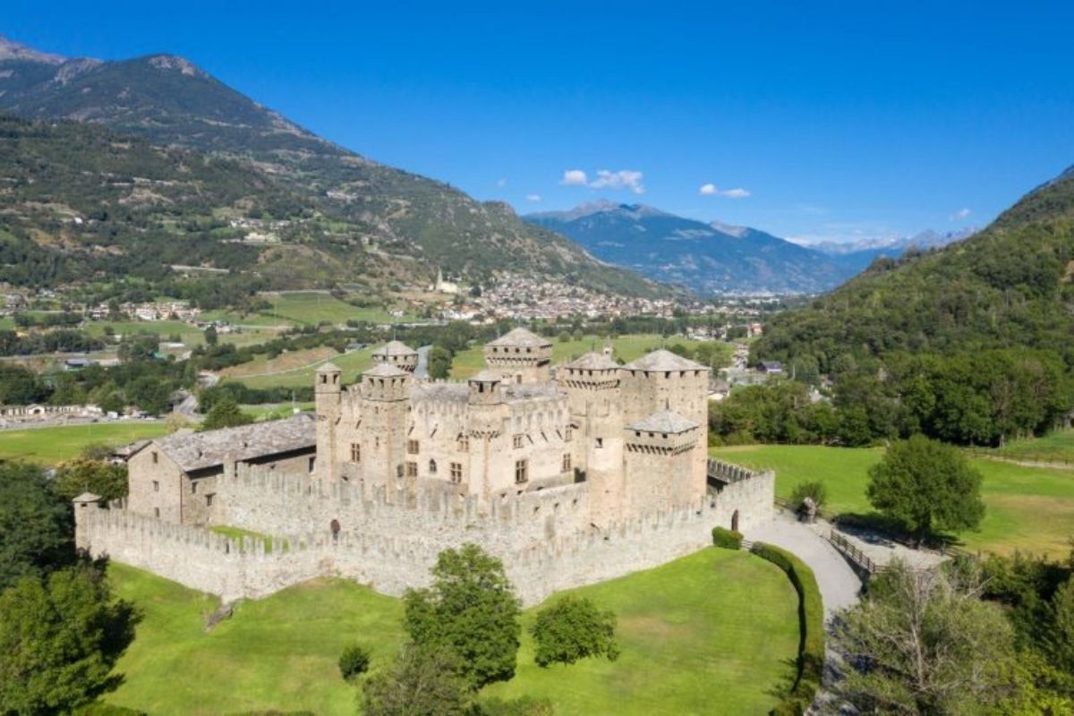 Vista panoramica del castello di Fénis al tramonto, circondato da monti