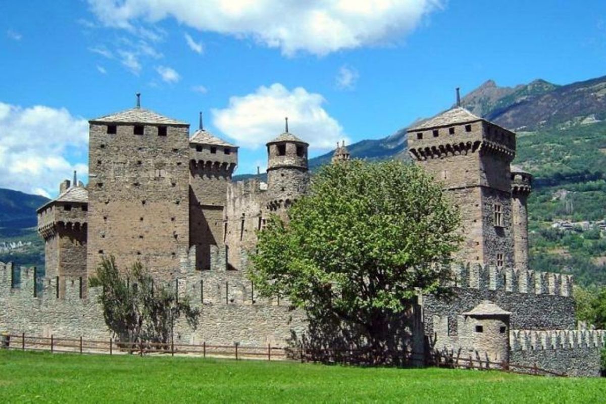 Scorcio del castello di Fénis circondato da verdi prati e montagne