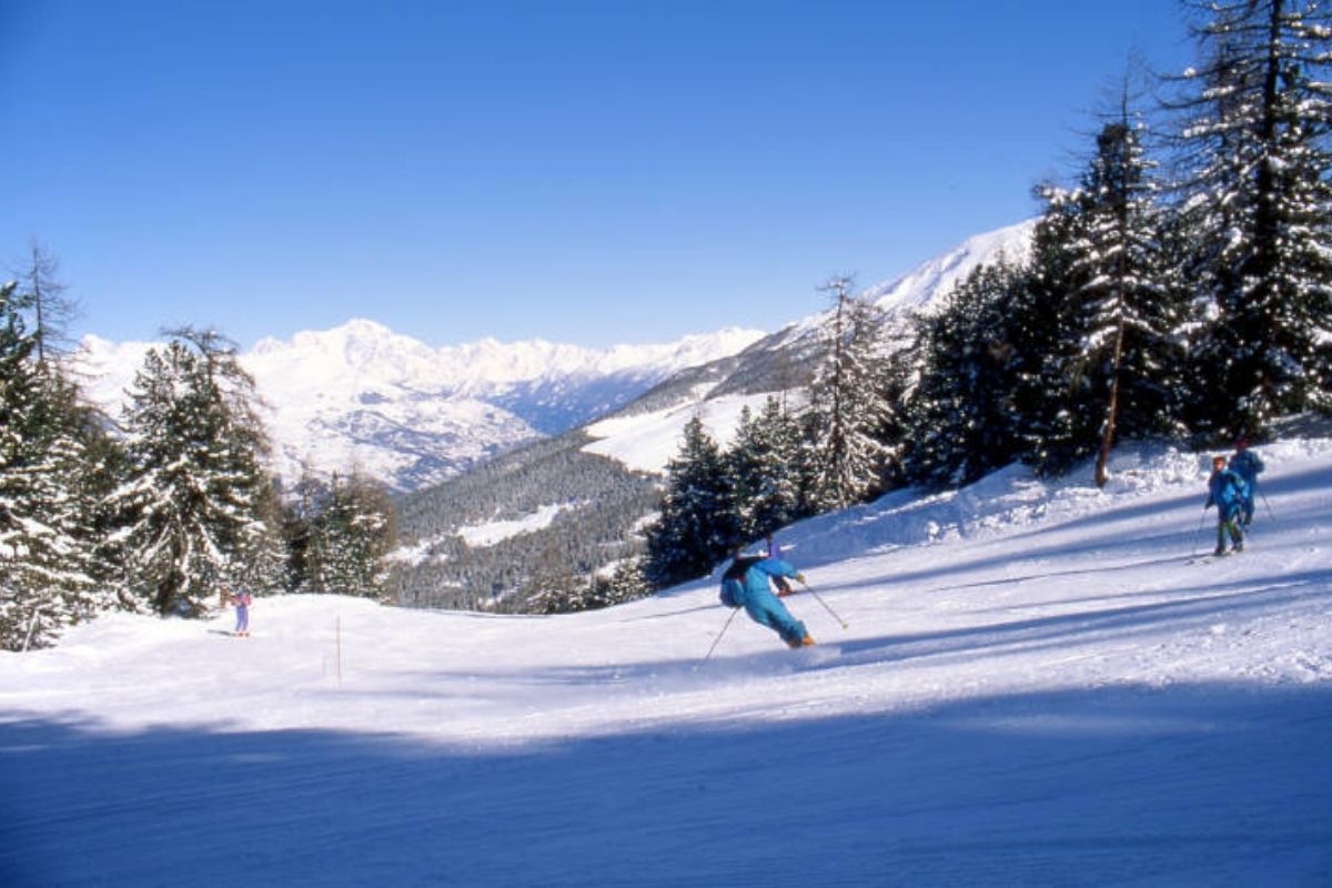 Scena invernale a Pila con sciatori e montagne